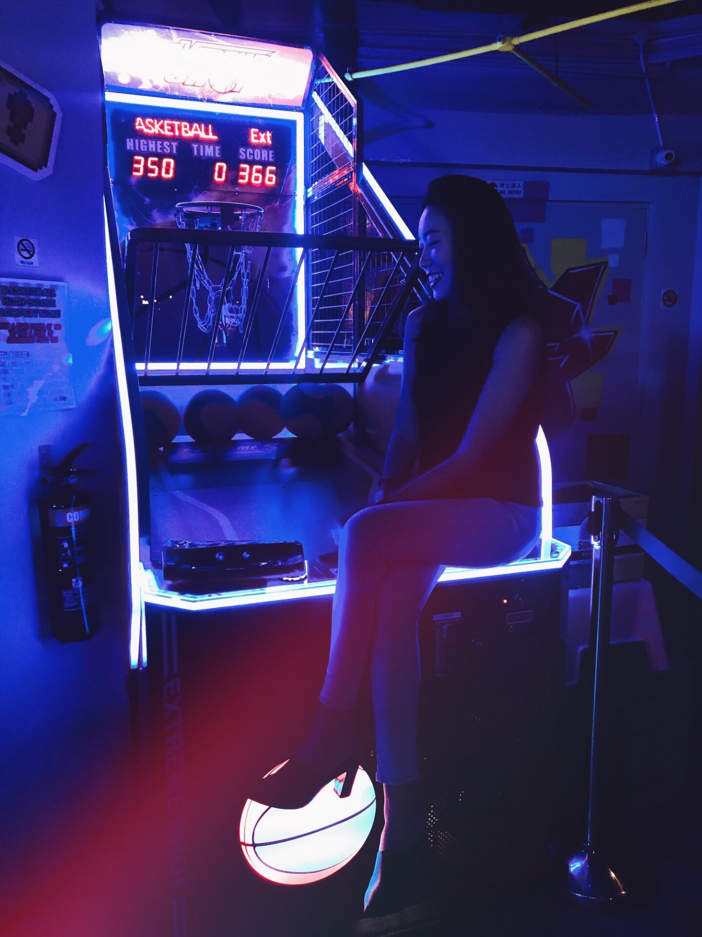 Woman sitting at the hoops machine in the arcade.